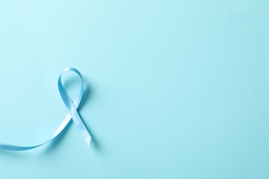 Blue ribbon on color background, top view. Cancer awareness