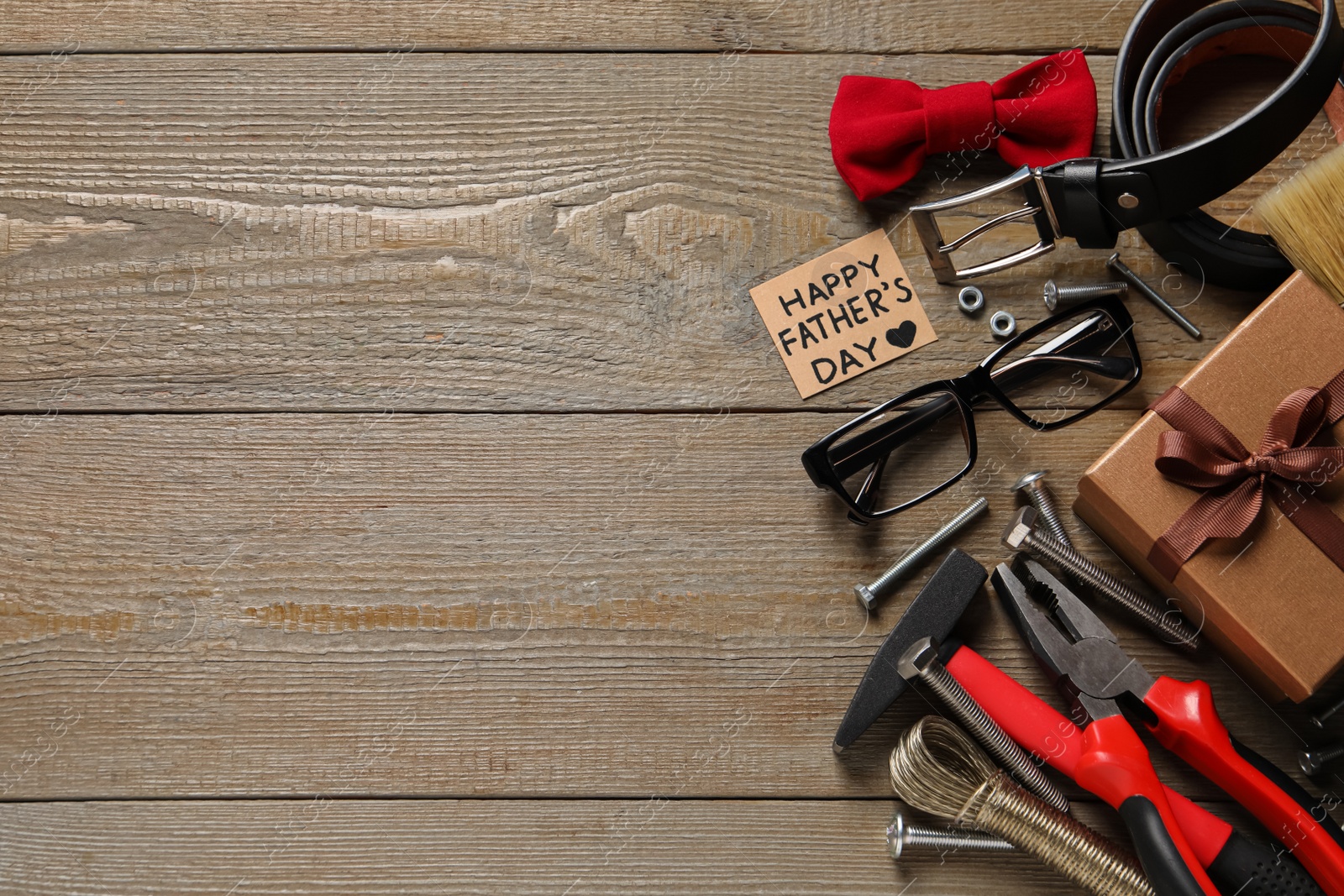 Photo of Card with phrase Happy Father's Day, different tools and men accessories on wooden background, flat lay. Space for text