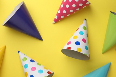Photo of Beautiful party hats on yellow background, top view
