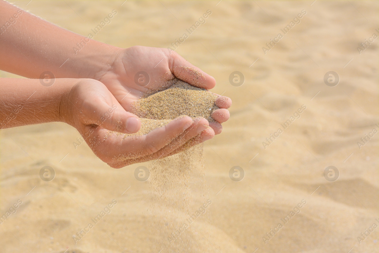 Photo of Child pouring sand from hands on beach, closeup with space for text. Fleeting time concept