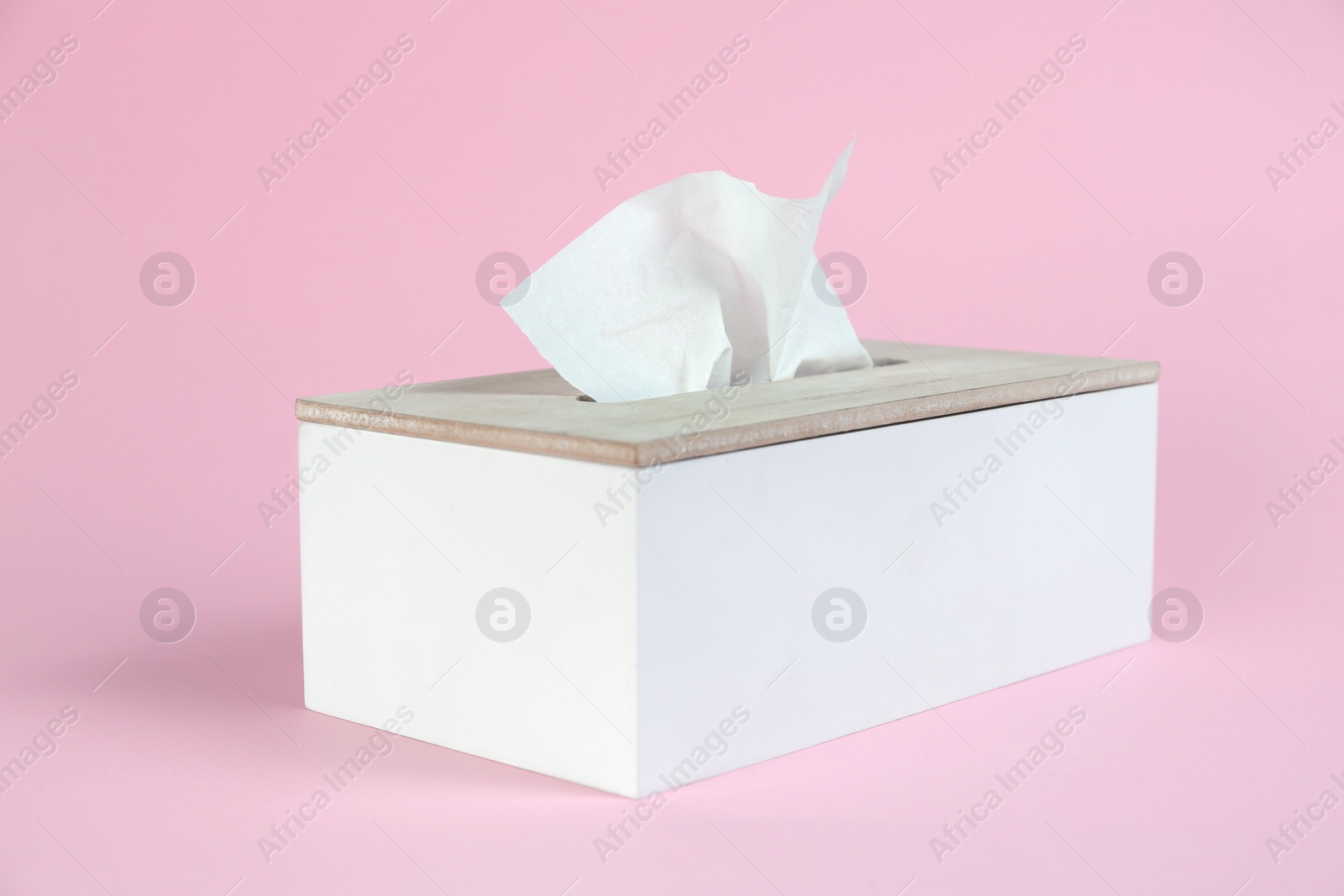 Photo of Holder with paper tissues on pink background