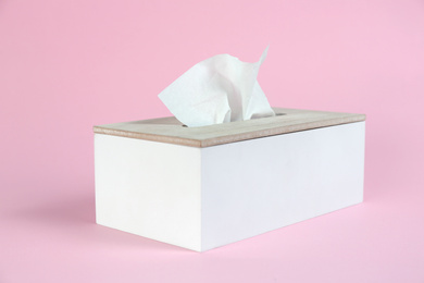 Photo of Holder with paper tissues on pink background