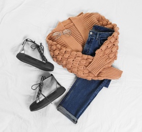 Photo of Flat lay composition with jeans, cardigan and shoes on white fabric