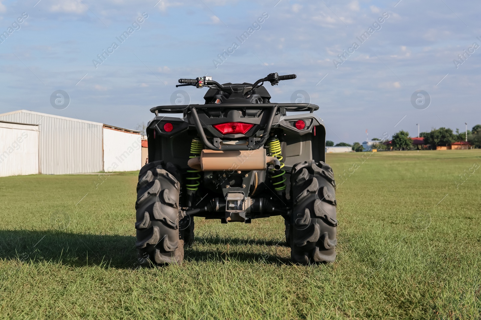 Photo of Modern quad bike in field near hangars on sunny day