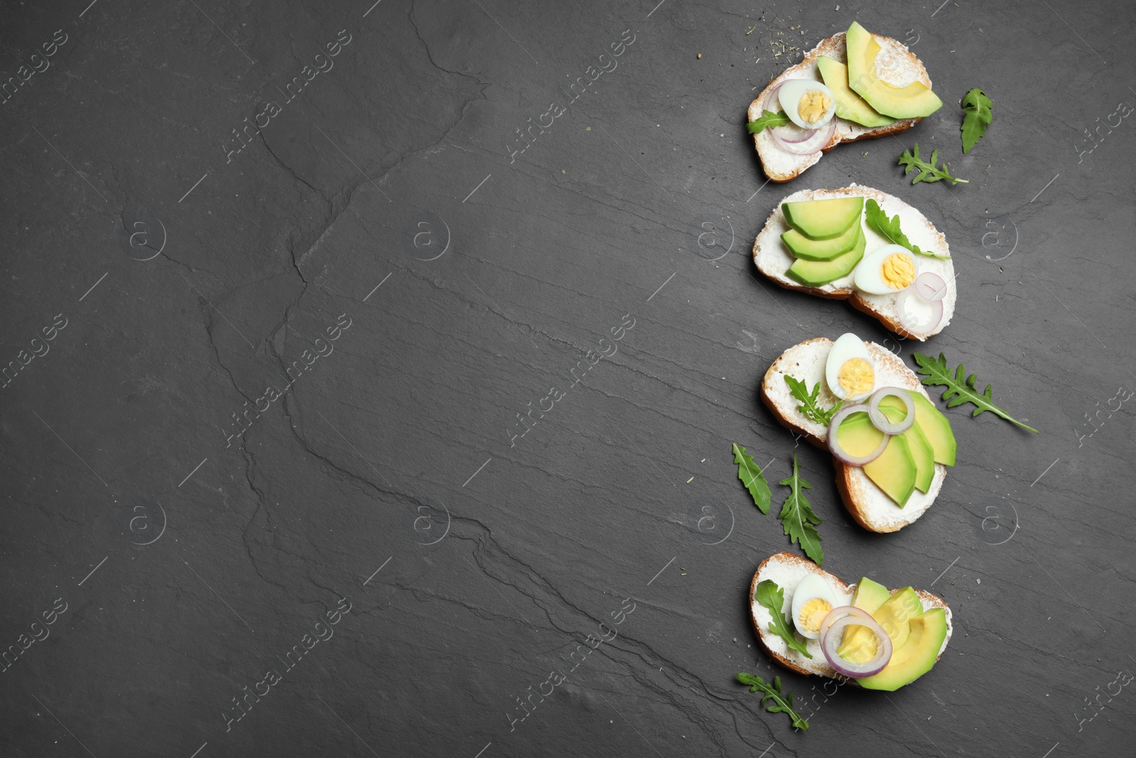 Photo of Delicious avocado sandwiches on dark table, flat lay. Space for text