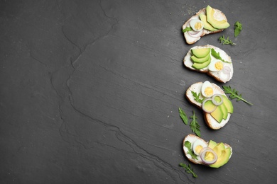 Photo of Delicious avocado sandwiches on dark table, flat lay. Space for text