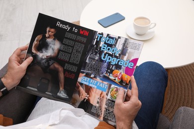 Man reading magazine in armchair at home, closeup