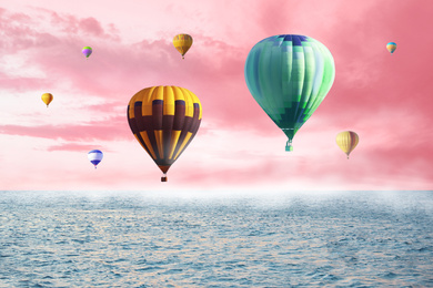 Image of Dream world. Hot air balloons in pink sky with clouds over misty sea
