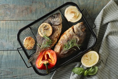 Delicious dorado fish with vegetables served on wooden table, flat lay