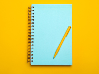 Light blue notebook and pen on yellow background, top view