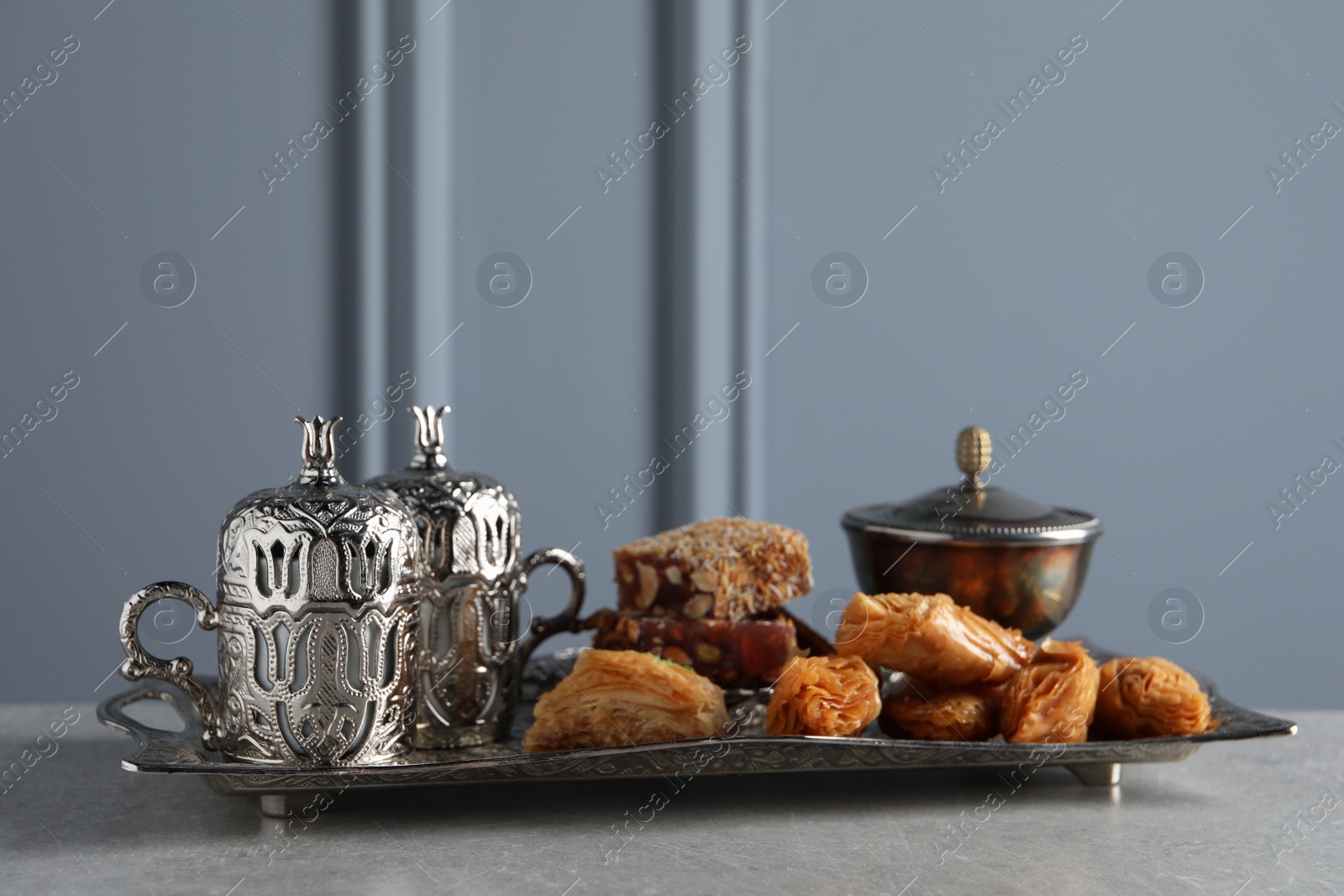 Photo of Tea, baklava dessert and Turkish delight served in vintage tea set on grey textured table