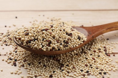 Photo of Spoon with raw quinoa seeds on table, closeup