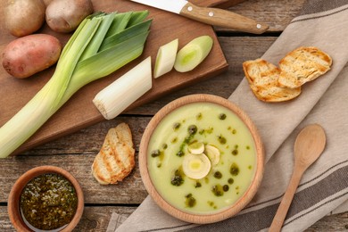 Photo of Delicious leek soup on wooden table, flat lay