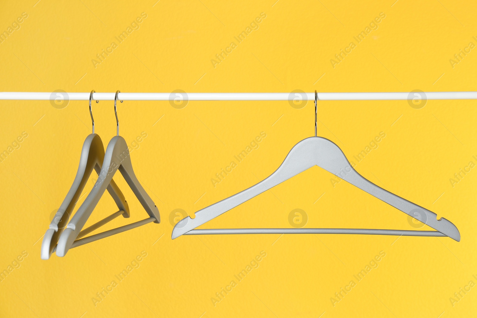 Photo of Metal rack with clothes hangers on color background