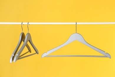 Photo of Metal rack with clothes hangers on color background