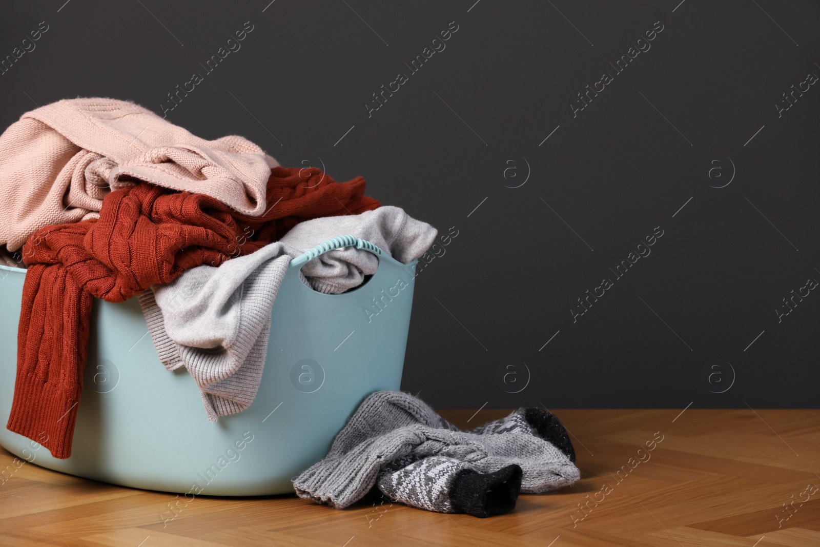 Photo of Laundry basket with clothes near dark grey wall. Space for text