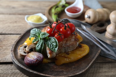 Delicious grilled meat and vegetables served on wooden table, closeup