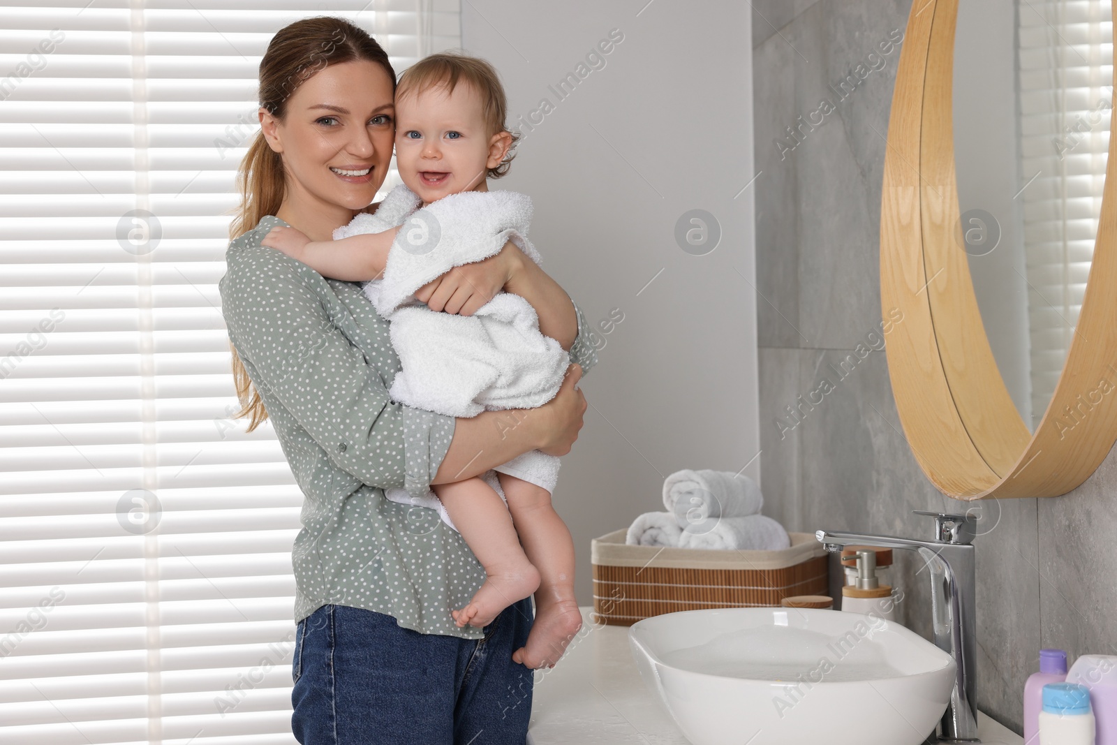 Photo of Mother holding cute little baby wrapped with towel indoors after bath, space for text