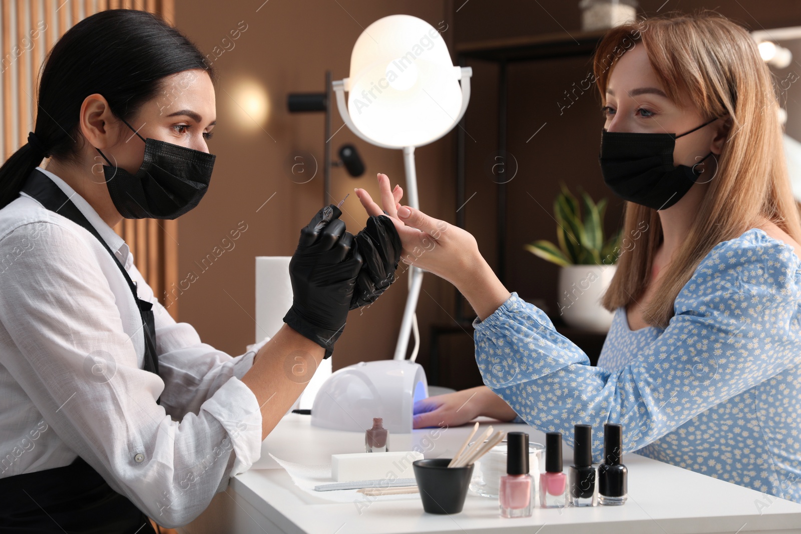 Photo of Professional manicurist working with client in salon. Beauty services during Coronavirus quarantine