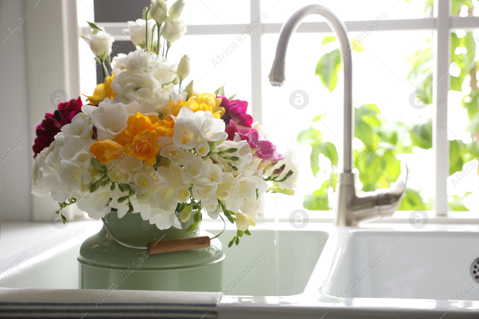 Photo of Beautiful bouquet with fresh freesia flowers in kitchen sink