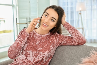 Photo of Attractive young woman talking on mobile phone at home