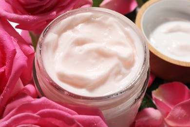 Photo of Jar of face cream among beautiful roses, closeup