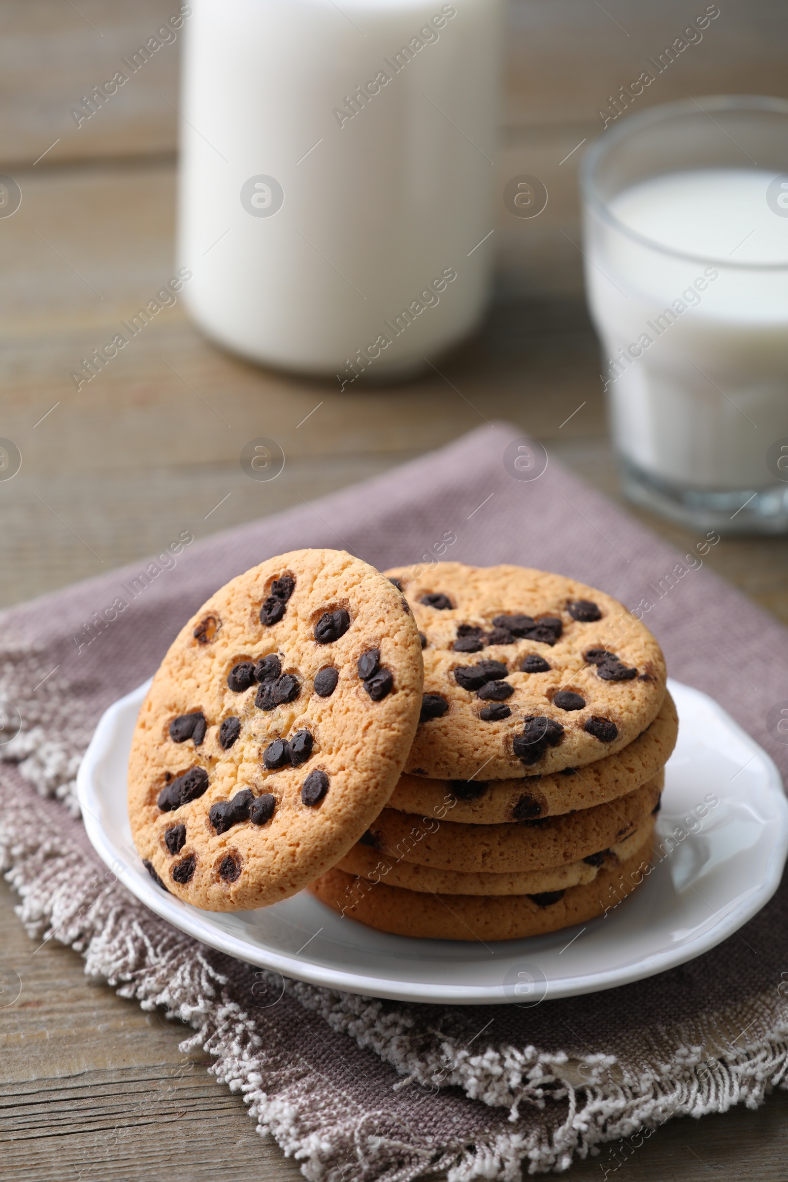 Delicious chocolate chip cookies and milk on wooden table Photo of Delicious chocolate chip cookies and milk on wooden table