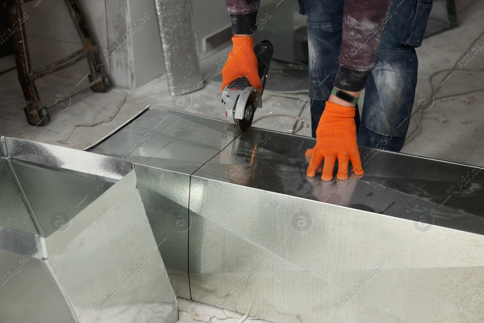 Photo of Worker cutting ventilation pipe indoors, closeup view