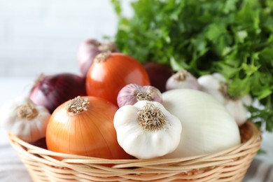 Photo of Fresh raw garlic and onions in wicker basket, closeup