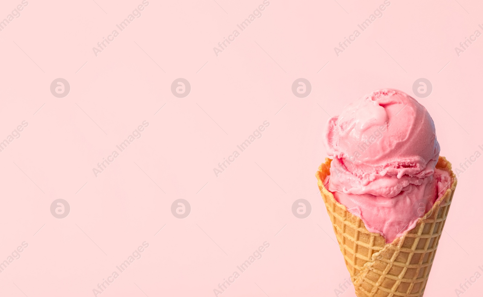 Photo of Delicious ice cream in waffle cone on pink background, closeup. Space for text