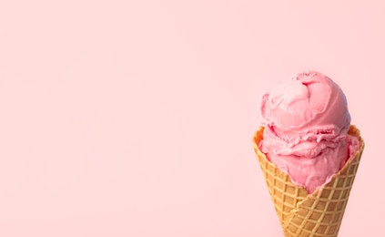 Delicious ice cream in waffle cone on pink background, closeup. Space for text