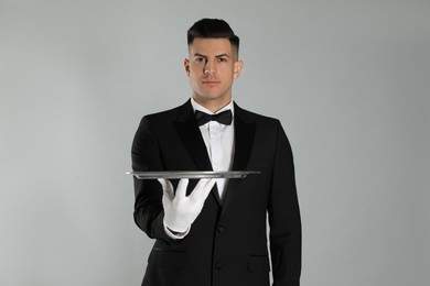 Photo of Handsome butler with tray on light grey background