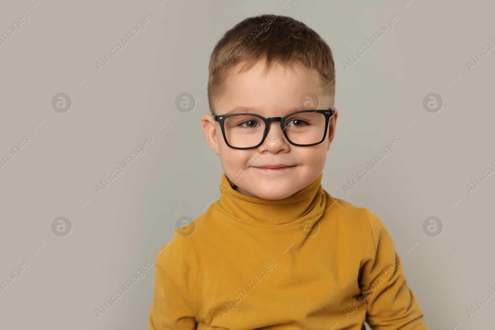 Photo of Cute little boy in glasses on light grey background. Space for text