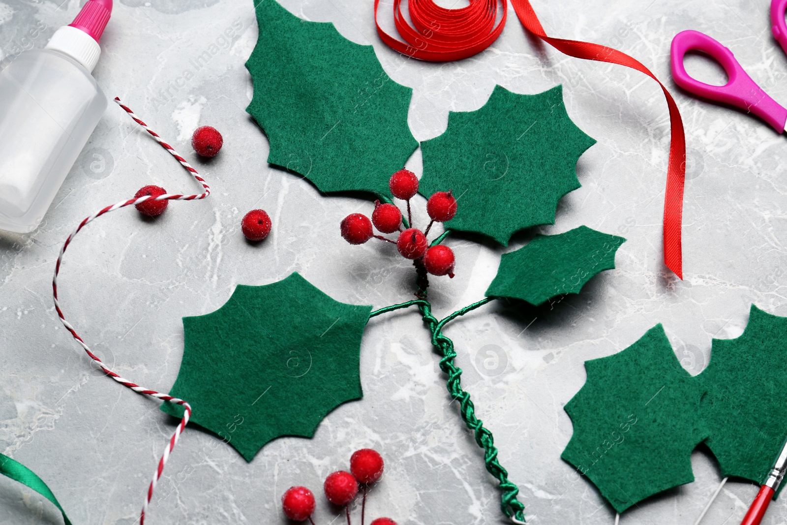 Photo of Set of instruments and materials for making mistletoe branch on grey table, flat lay