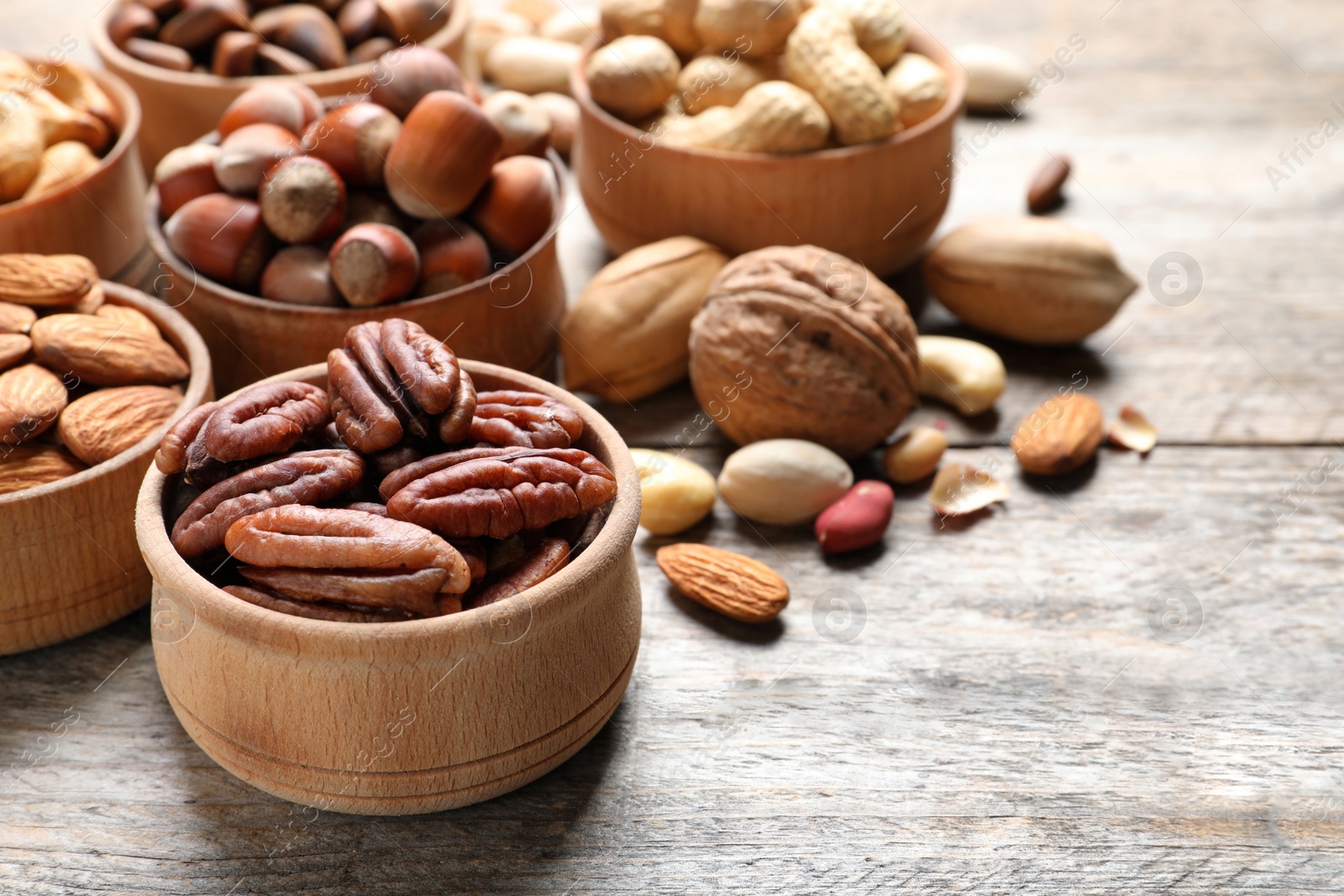 Photo of Bowls with organic nuts on wooden table, space for text. Snack mix