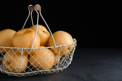 Photo of Ripe apple pears in basket on black table. Space for text