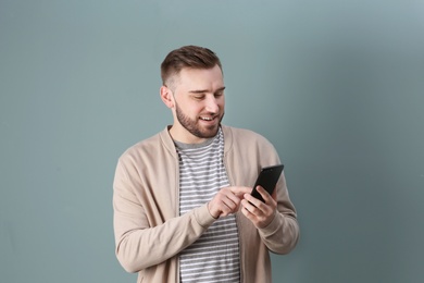 Photo of Portrait of confident young man with mobile phone on color background