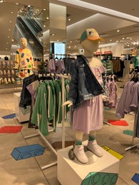 Photo of Beautiful children's clothes on mannequins and racks in fashion store