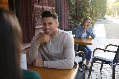 Photo of Jealous ex girlfriend spying on couple in outdoor cafe