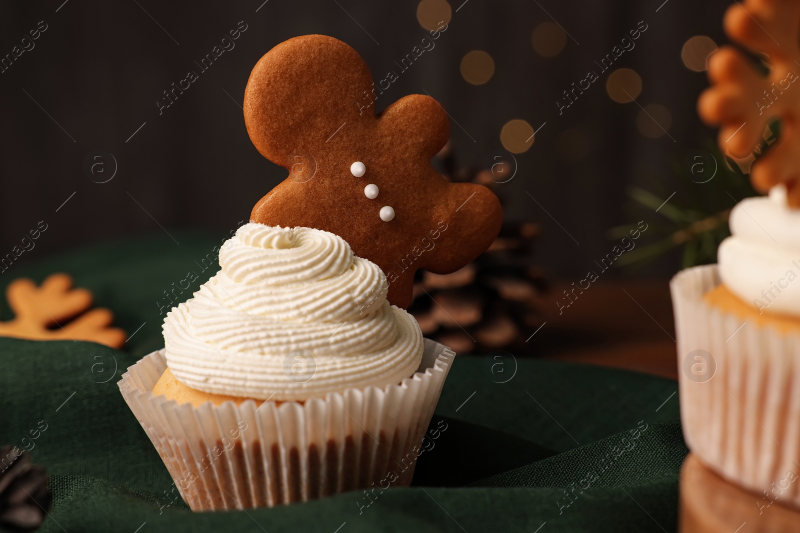 Photo of Tasty Christmas cupcake with gingerbread man on green fabric
