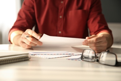 Photo of Man writing letter at white table in room, closeup