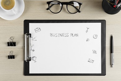 Flat lay composition of clipboard with words Business Plan on wooden table