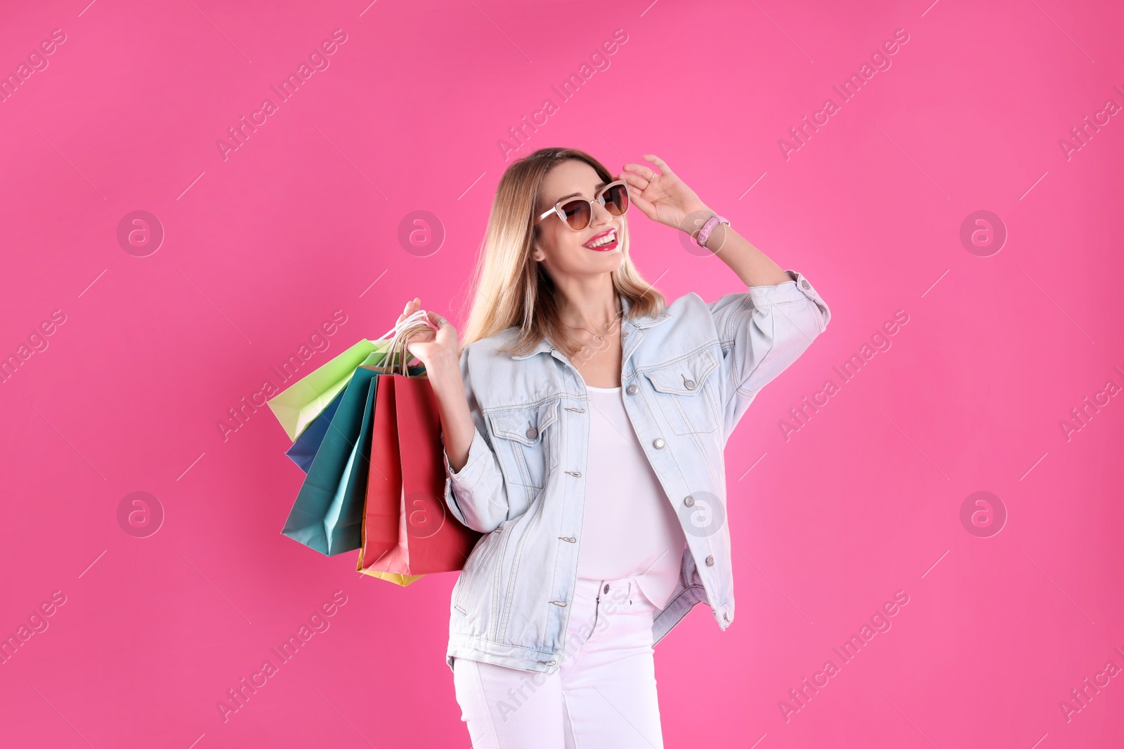 Photo of Beautiful young woman with shopping bags on color background