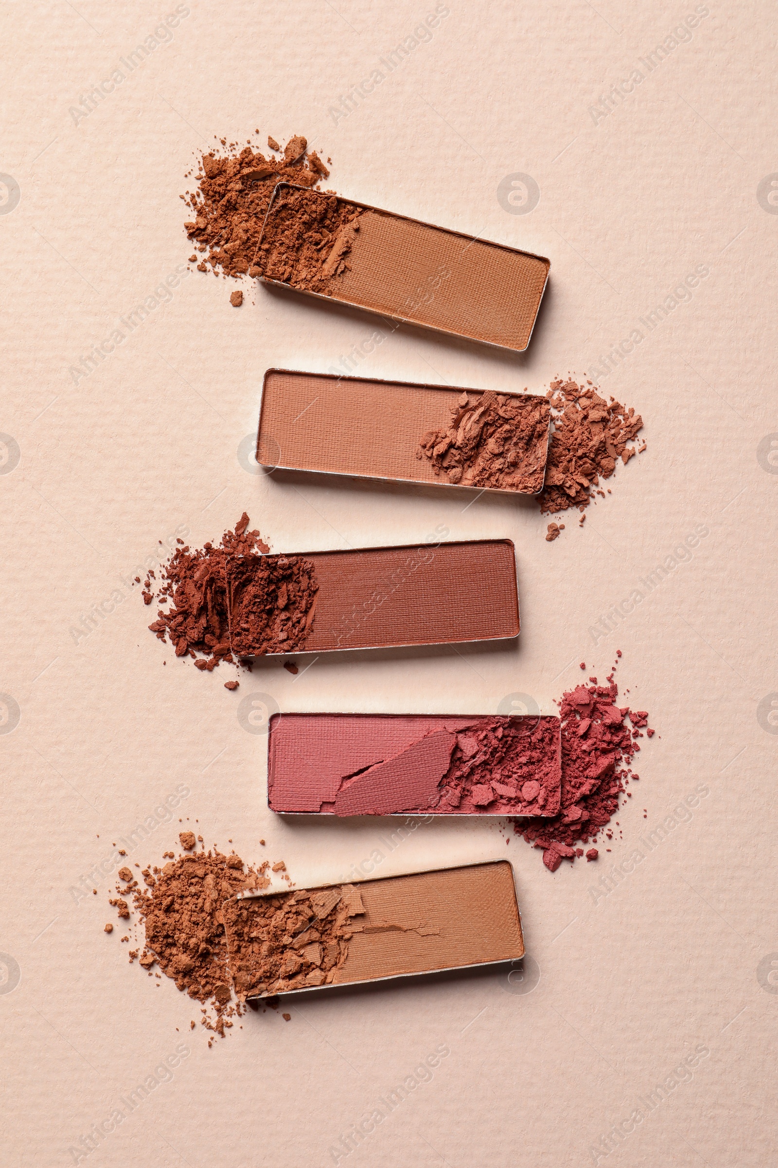 Photo of Different crushed eye shadows on beige background, flat lay