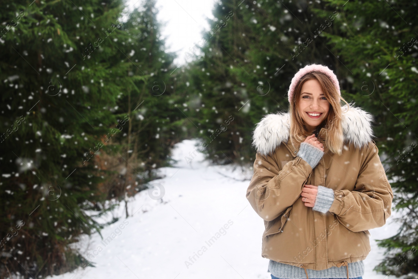 Photo of Young woman in snowy conifer forest, space for text. Winter vacation