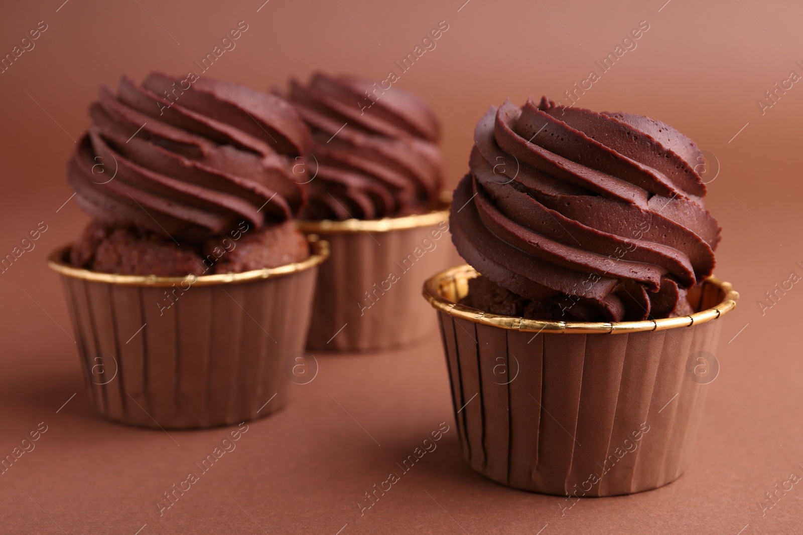 Photo of Delicious chocolate cupcakes on brown background, closeup