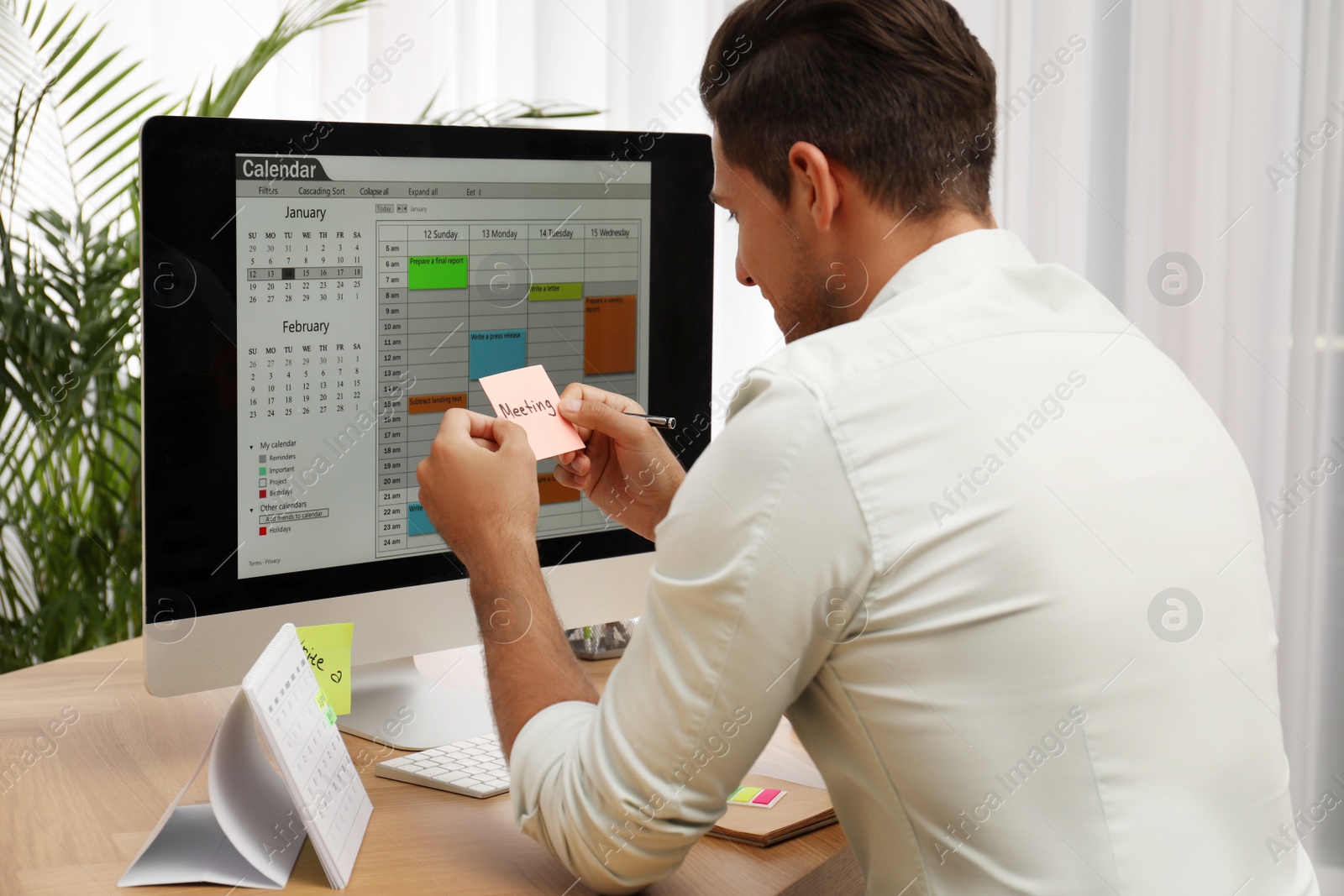 Photo of Handsome man using calendar app on computer in office