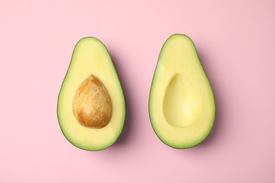 Cut fresh ripe avocado on pink background, flat lay