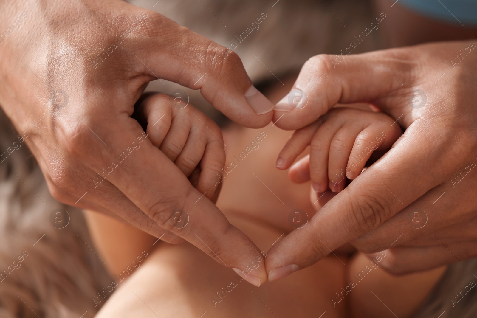 Photo of Father with his newborn baby, closeup. Man making heart shape with hands. Lovely family