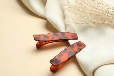 Photo of Stylish hair clips and fabric on beige background